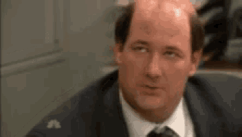 a bald man in a suit and tie is looking at something .