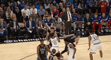 a group of basketball players are playing on a court with a crowd watching