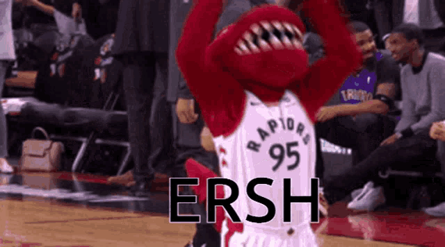 a raptors mascot wearing a 95 jersey stands on a basketball court