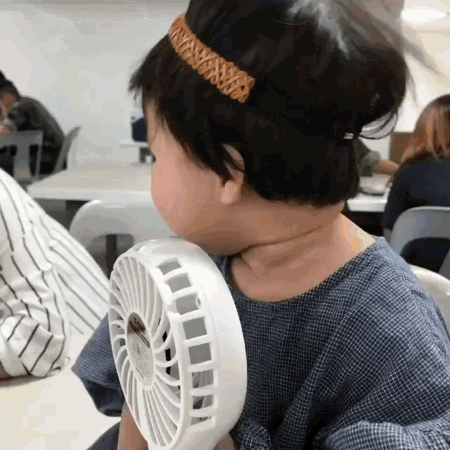 a little girl is holding a small white fan in her hand