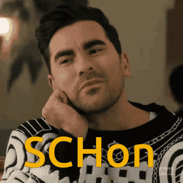 a man in a black and white sweater with the word schon written on it