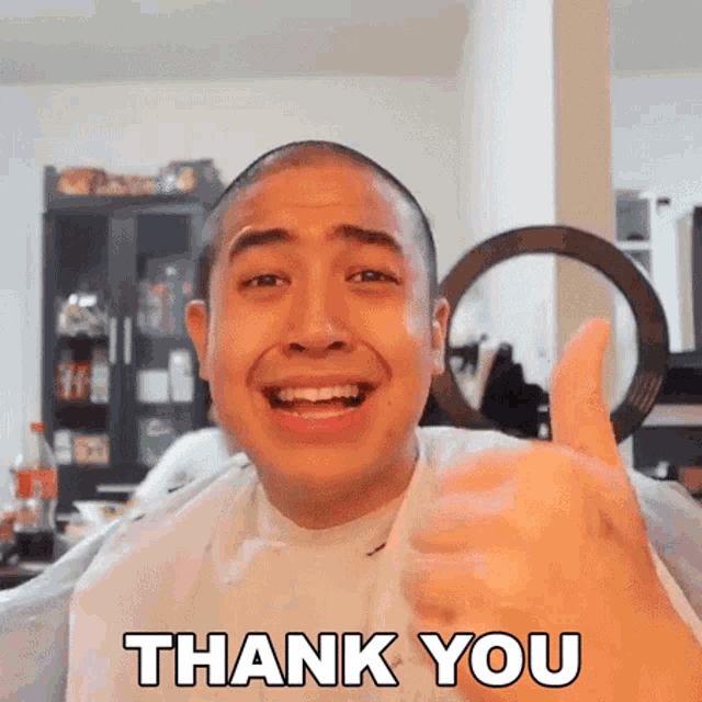 a man with a shaved head is giving a thumbs up and says thank you