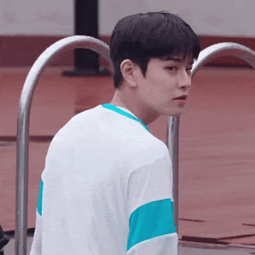 a young man wearing a white shirt and blue sleeves is standing next to a pool .