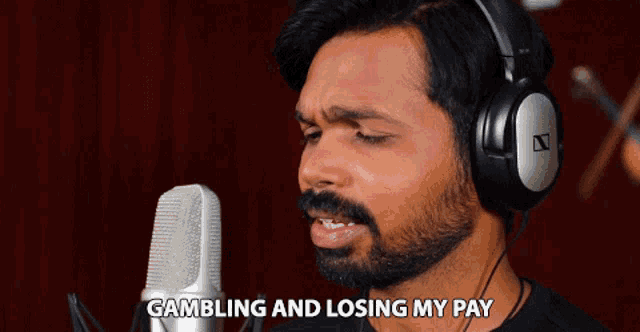 a man wearing headphones singing into a microphone with the words gambling and losing my pay above him