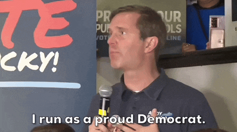 a man speaking into a microphone with the words i run as a proud democrat behind him