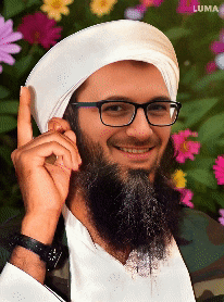 a man with a beard wearing glasses and a white turban stands in front of flowers