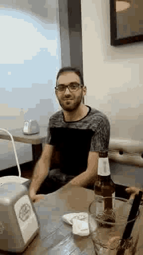 a man is sitting at a table with a bottle of beer in front of him .
