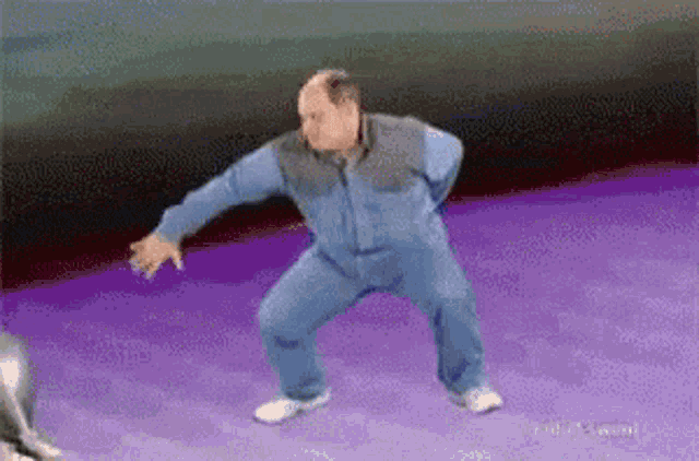 a bald man is dancing on a purple surface .