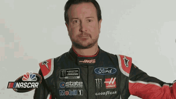 a man in a ford racing suit stands in front of a nbc nascar logo