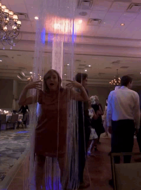 a woman in a red dress is standing in front of a curtain that looks like a waterfall