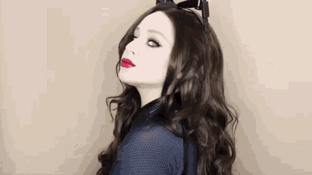 a woman wearing a cat ear headband and red lipstick is looking at the camera .