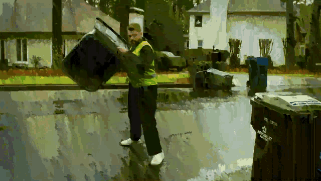 a man in a yellow vest is carrying a trash can that says recycling