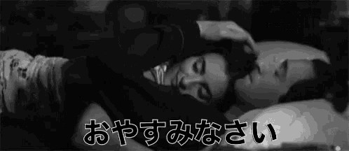 a black and white photo of a man and woman sleeping in a bed with chinese writing .