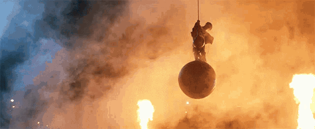 a person is hanging from a rope while a large ball is hanging from the ceiling .