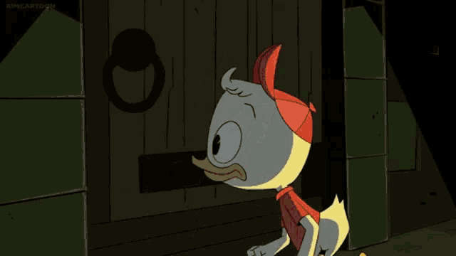 a cartoon duck wearing a red shirt and a red hat is standing in front of a wooden door .