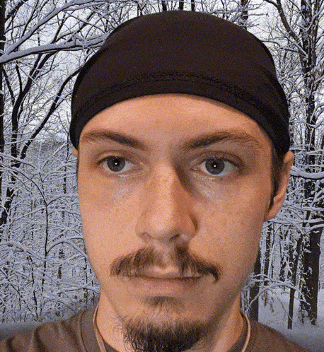 a man with a beard wearing a black headband looks at the camera