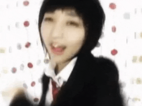 a woman in a school uniform is dancing in front of a white wall .