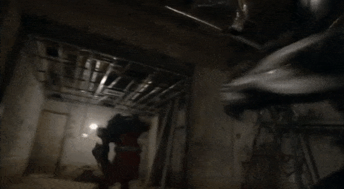 two people are fighting in a dark room with a light on the ceiling