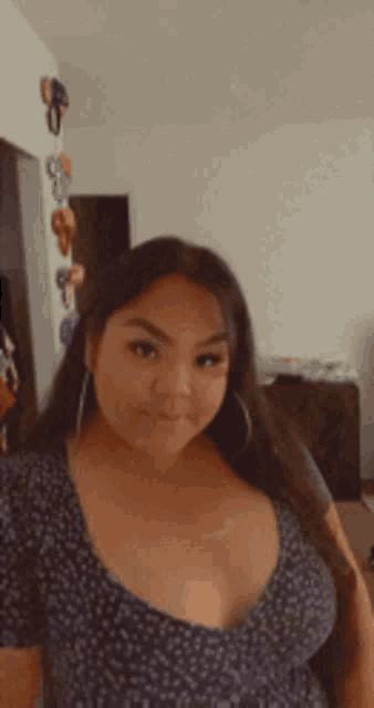 a woman with a very large breast is smiling for the camera in a room .