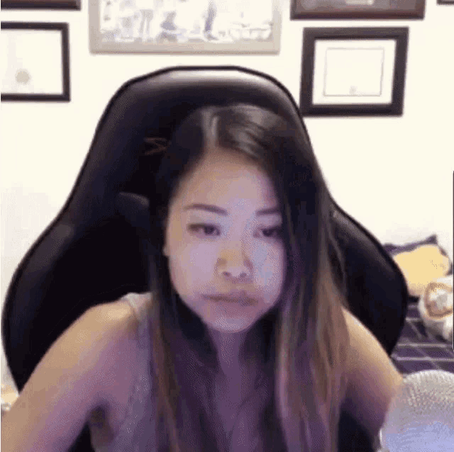 a woman is sitting in a gaming chair with a microphone in front of her .