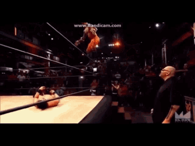 two men are wrestling in a wrestling ring and one of them is falling .
