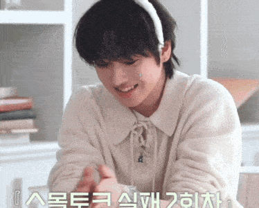 a young boy wearing a white sweater and a white headband with korean writing on it