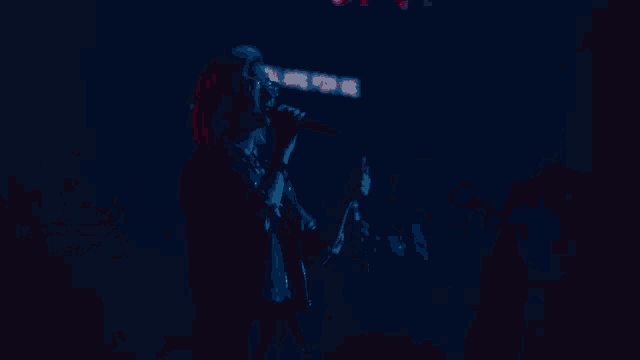 a woman singing into a microphone in front of a red and blue background