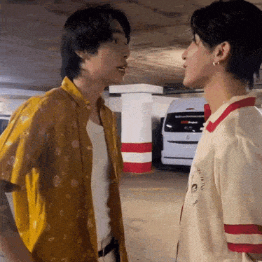 a couple of men are standing next to each other in a parking garage .