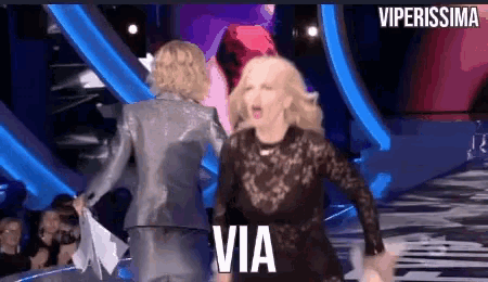 two women are dancing on a stage and the words via are on the bottom right