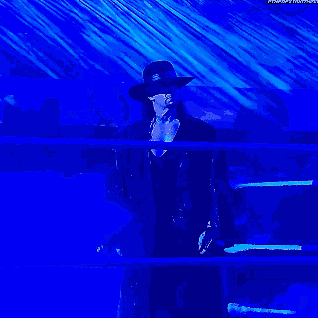 a man in a black hat is standing in a ring with a microphone in his hand ..