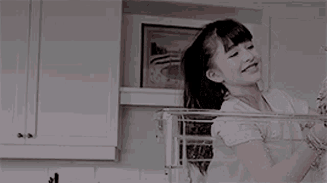 a little girl is standing in a kitchen with a picture on the wall .