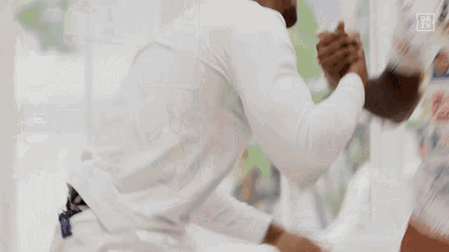 a blurry picture of two men fighting with dazn written on the bottom right