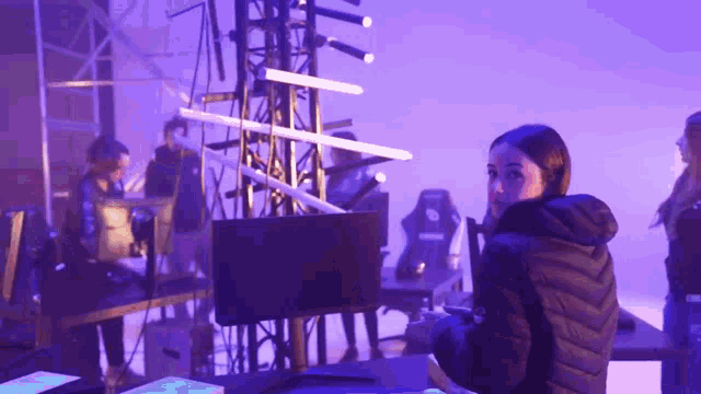 a woman in a black jacket is playing a video game in a dark room