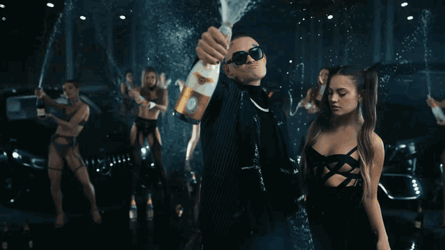 a man in a suit is holding a bottle of champagne in his hand