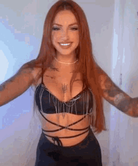 a woman with long red hair is wearing a black bra and black skirt .