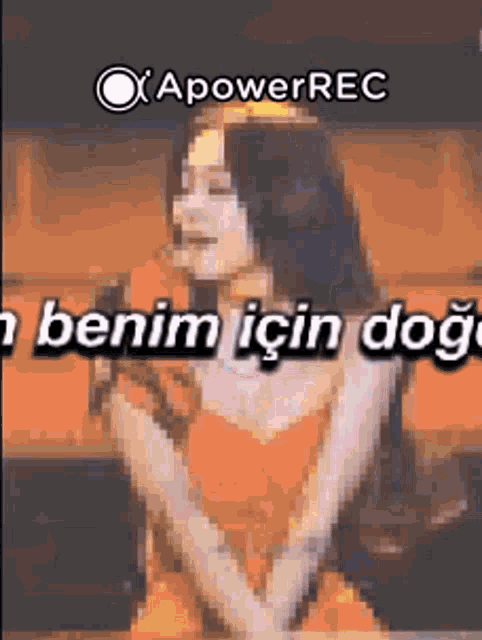 a woman in an orange dress is singing into a microphone with a caption that says " benim için dog " .