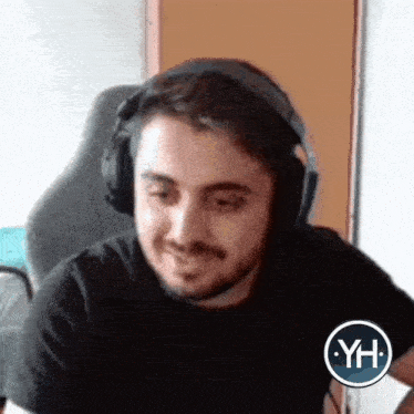 a man with a beard is wearing headphones and smiling while sitting in a chair .