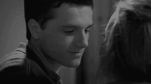 a man and a woman are kissing each other in a black and white photo .