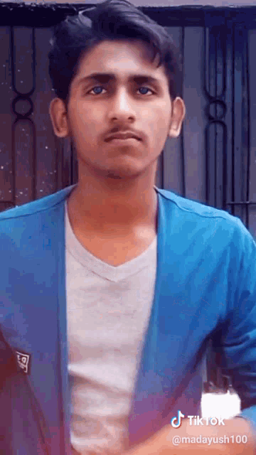 a young man is wearing a blue jacket and a white shirt