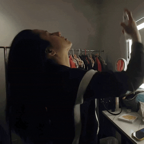 a woman is spraying her face with a spray bottle in front of a mirror