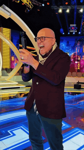a bald man in a suit and scarf is standing in front of a stage with a sign that says grande finale