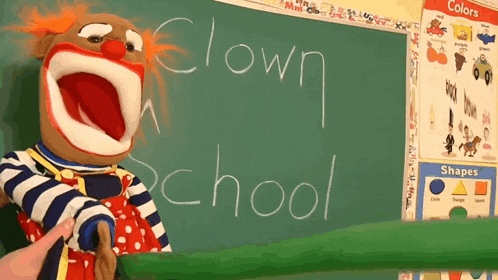 a clown puppet stands in front of a blackboard with the word clown written on it