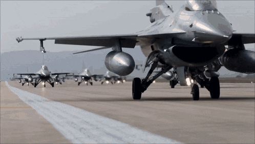 a row of fighter jets are lined up on a runway and one of them has the letter n on the nose