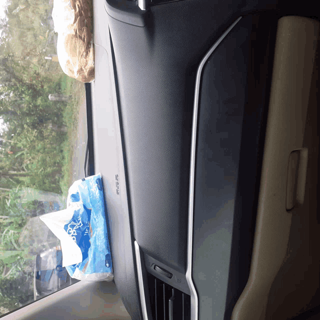 a bag of tissues sits on a car dashboard