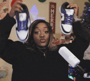 a woman in a black sweater is holding up a pair of shoes
