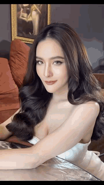 a woman in a white dress is sitting in front of a couch