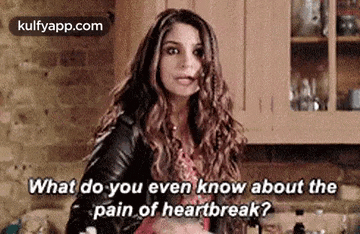 a woman is sitting in a kitchen and talking to someone about the pain of heartbreak .