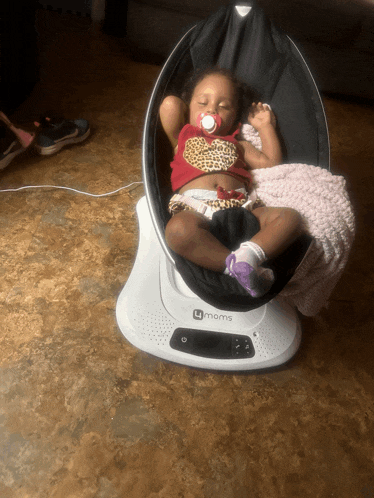 a baby is laying in a 4moms chair
