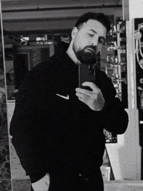 a man taking a selfie in front of a mirror wearing a black nike hoodie
