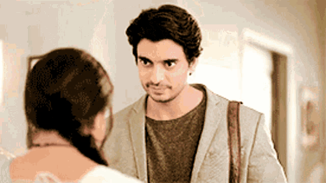 a man in a suit is looking at a woman in a white dress